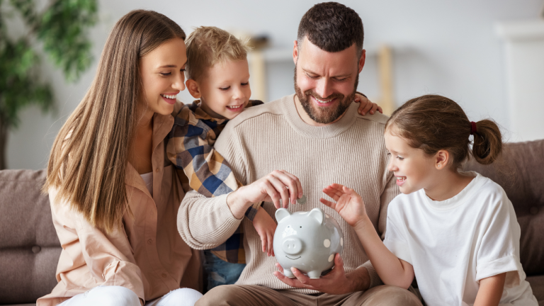 Young family sitting together putting money in a piggy bank