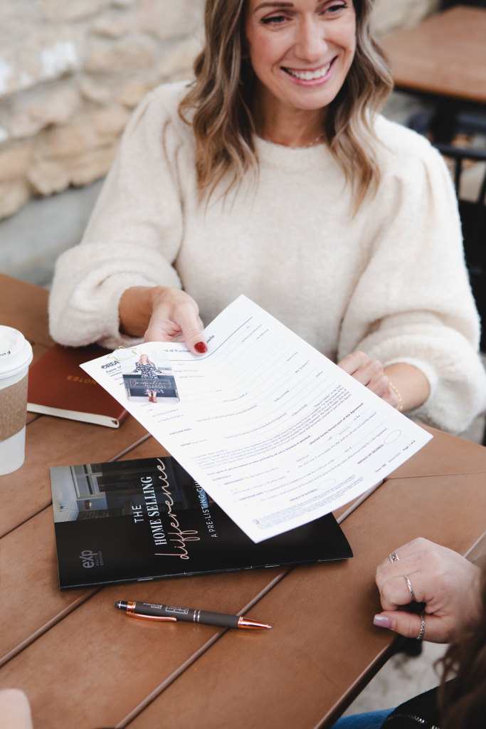 jacqueline clement living in dufferin county real estate agent handing paperwork to a client while smiling